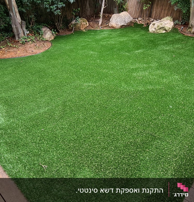 דשא סינתטי עם אבנים ועצים מסביב